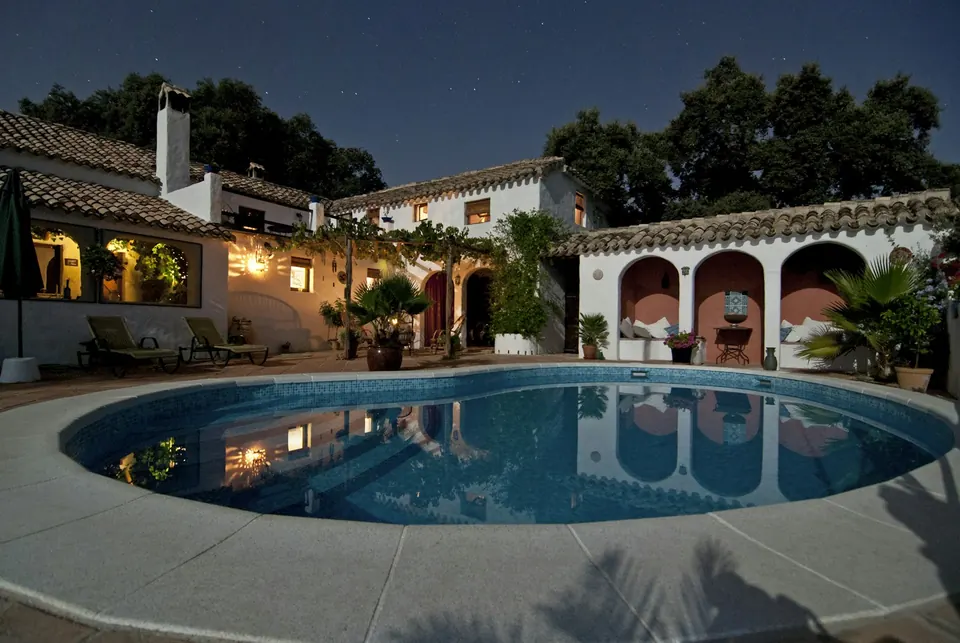 Villa patio and pool glowing with warm lighting at night