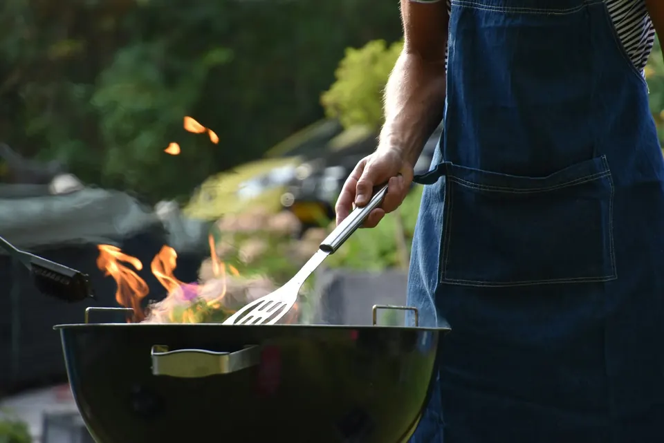 Chef grilling over open flame in an outdoor kitchen